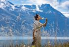 Woman tasting cider with views of the Hardangerfjord